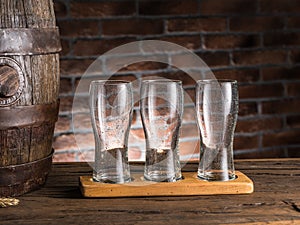 Empty beer glasses near a cask on wooden table. Craft brewery