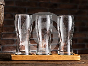 Empty beer glasses near a cask on wooden table. Craft brewery