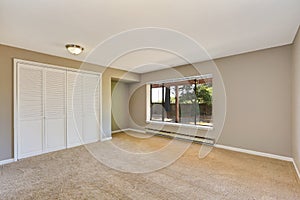 Empty beige room with closet and carpet floor.
