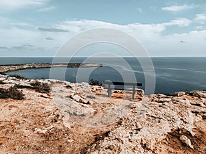 An empty bench on a cliff above the sea. Cape Greco view point near Ayia Napa. Travel, relaxation and tranquility.