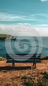 Empty bench on cliff overlooks peaceful sea, ideal for solitude