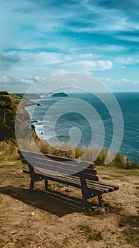 Empty bench on cliff overlooks peaceful sea, ideal for solitude