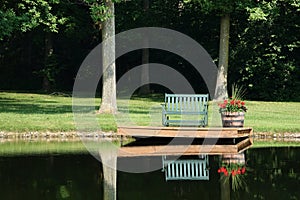 Empty Bench and Geraniums in Barrel Beside Pond for Quiet Reflection