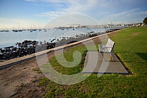 An empty bench on grass by the waters edge.