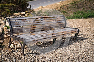 An empty bench made of wood and metal in a park on the waterfront, empty during a pondemia.