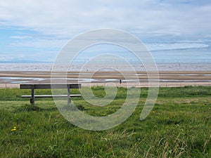 Empty bench overlooking the beach at blundel sands in crosby, merseyside with burbo bank wind farm in the distance