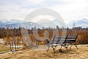 Empty bench in the park and mountains in the background. Almaty