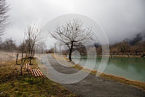 Empty bench at park near pond by foggy day, minimalistic cold season scene. bench at the lake in the fog in the forest. Bench near