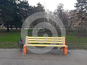 An empty bench in the park, painted in yellow and red