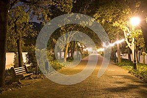 Empty bench on pathway at night