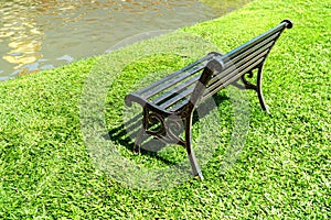 An empty bench beside a pond in the park