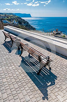 Empty benches on sea shore in a park. Sea view from mountain. Travel, relax or loneliness concept. Wooden bench on open space