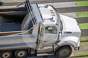 An empty big rig tip truck moves along city street along pedestrian crossing road