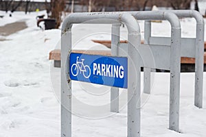 Empty bike parking in snowy public park at cold winter, urban bicycle station in city recreation zone, cloudy weather