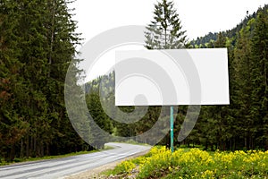 Empty billboard or big board on side of road with green forest and hills on background. Advertising blank, mock up, copy space for