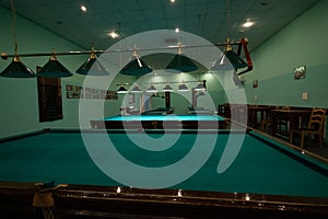 Empty billiard room with green tables illuminated by lamps. Beautiful game room for billiards without people. Many pool