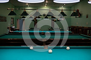 Empty billiard room with green tables illuminated by lamps. Beautiful game room for billiards without people. Many pool