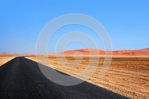Empty black asphalt long road, Namib desert dunes and blue sky background, transportation design template, nobody, copy space