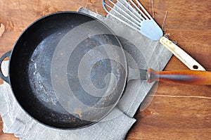 Empty black cast-iron frying pan and iron spatula on the table