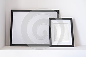 Empty black frames, posters, white canvas, mock up on a white wall, bedroom, gallery template, close up