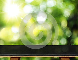 Empty black marble table and blurred garden bokeh light background. Mock up for display or montage