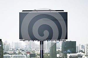 Empty black mock up billboard in dull city sky. Commercial concept.