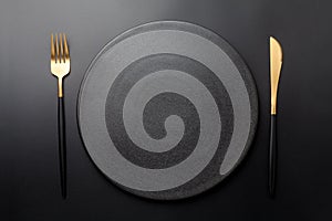 Empty black plate with fork and knife