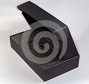 Empty black rectangular cardboard box with partly open lid