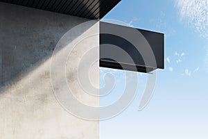 Empty black rectangular stopper or banner hanging on concrete building with shadows and bright blue sky view. Bar, restaurant,