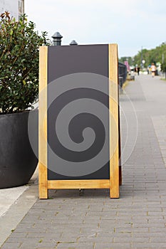 Empty black sandwich chalkboard menu board stand on a street