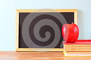 Empty blackboard , apple and stack of books. back to school concept.