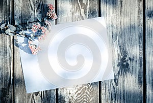 Empty, blank greeting card and pink field flowers on aged wooden background in sunlight. Flat lay. Top view with copy space, vinta