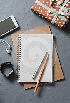 Empty blank notebook, gift box, phone on office desk top view.