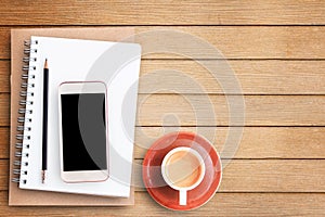 Empty blank paper notebook and smart phone on brown wooden table