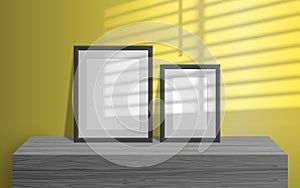 Empty blank picture frames on wooden table window light blinds effect on the yellow wall mock up