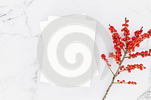 Empty blank white magazine cover mock up and branch with red berries on white marble table background