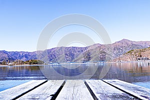 Empty blank wood plank or brown table. Landscape forest Lake with mountain blue sky and bright sunlight in background.