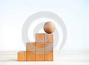 Empty blank wooden cube blocks build as a steps with the sphere one on top, isolated on wood desk on white background.