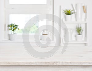 Empty bleached wooden table and kitchen window shelves blurred background