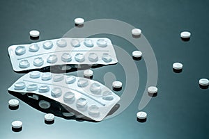 Empty blister packs, white disk-shaped tablets on black mirror background