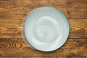 Empty blue ceramic plate on woden table