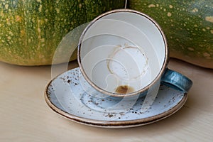 An empty blue coffee cup with traces of coffee at the bottom lies tilted on a saucer