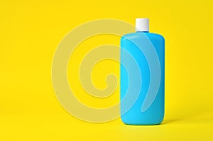 Empty blue plastic bottle on a yellow background