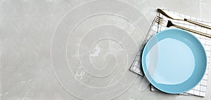 Empty blue plate with cutlery and napkin on grey marble table, flat lay. Space for text
