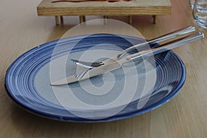 Empty blue plate with fork and knif over it