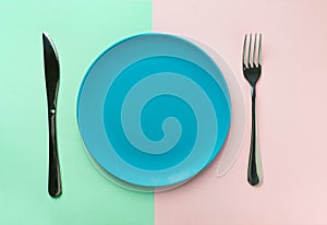 Empty blue plate fork and knife on duotone green pink background. Healthy diet meal planning concept. Mockup template