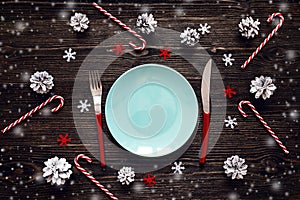 Empty blue plate, knife, spoon and fork with candy canes, christ