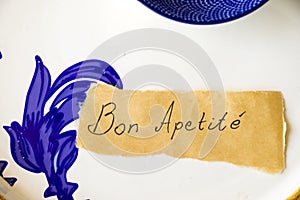 Empty blue tableware, paper and Bon apetite letter and text photo