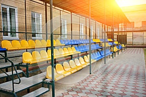 Empty blue and yellow sports seats of the grand stand at the back yard of school on the stadium