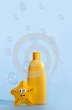 Empty bottle of baby washing gel, bath foam, liquid soap or shampoo with yellow star fish and flying soap bubbles